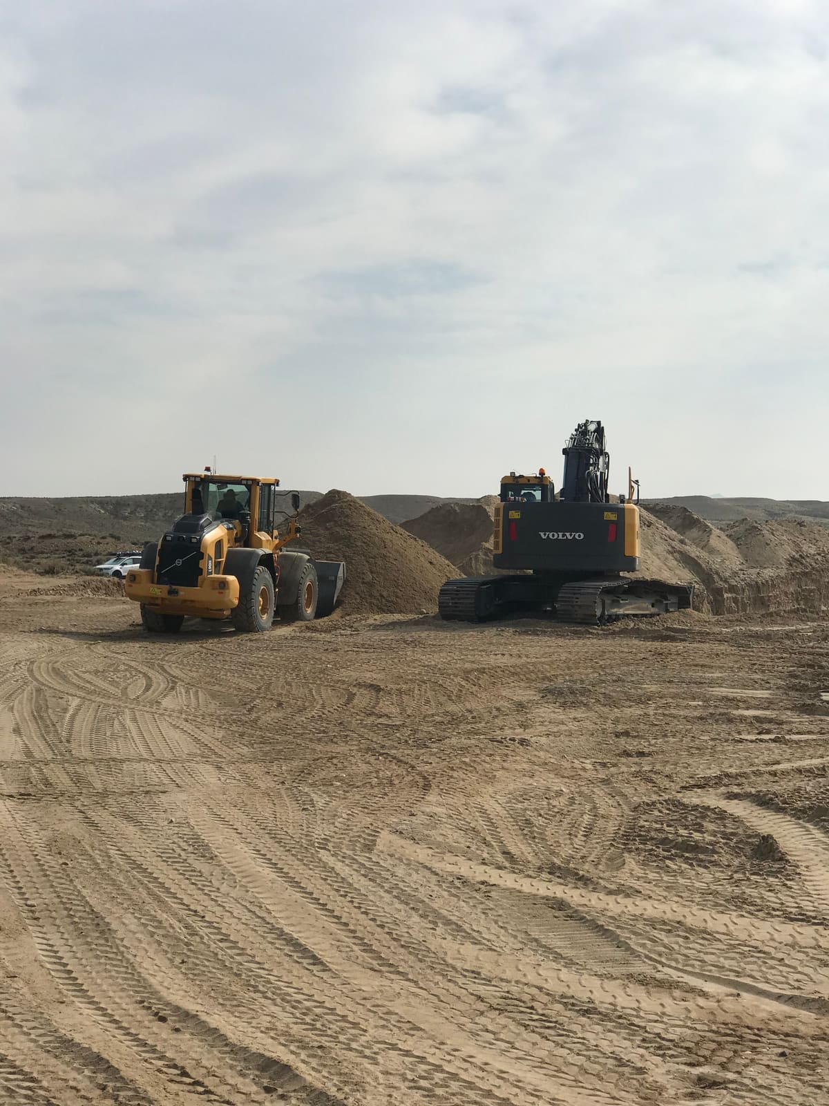 Excavator and loader moving terrace gravel to the wash plant during a bulk-sampling season.