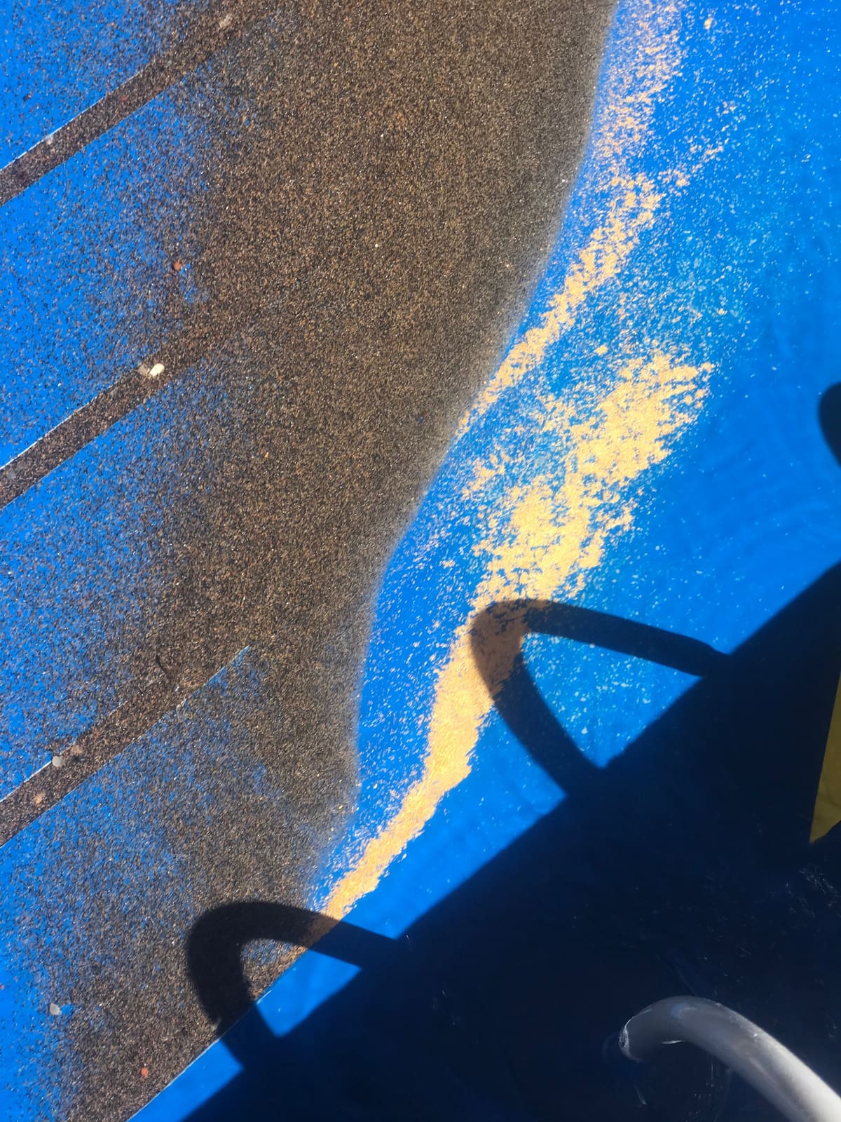 Heavy black sand and gold concentrate streaking across a blue sluice mat.