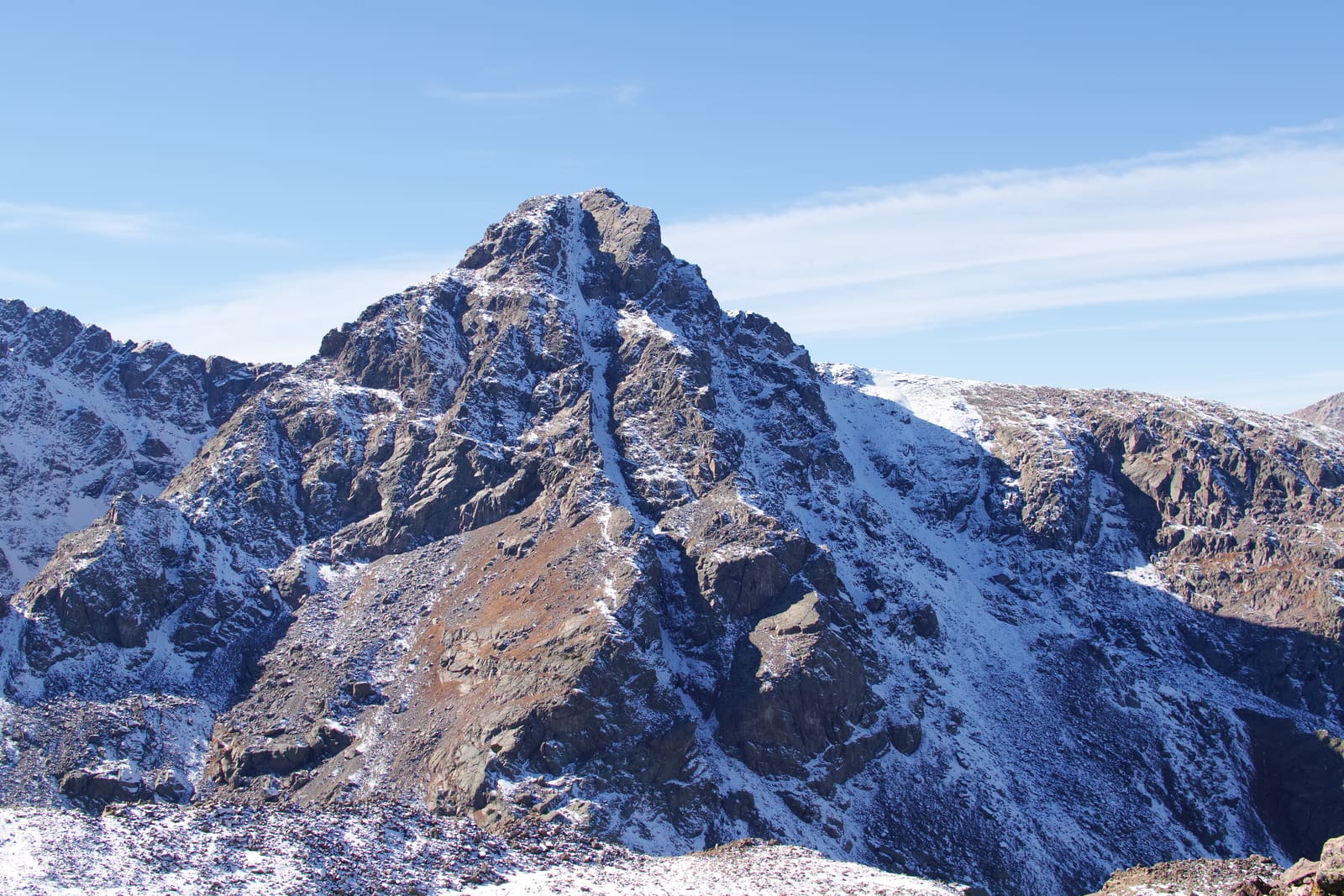 A snow-dusted peak rising above the basin country under a deep blue sky.