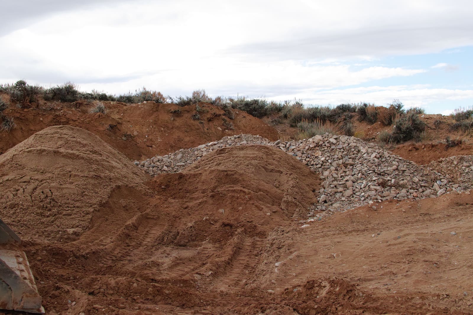 A freshly worked cut into pale terrace gravels, with cobbles and sand exposed.